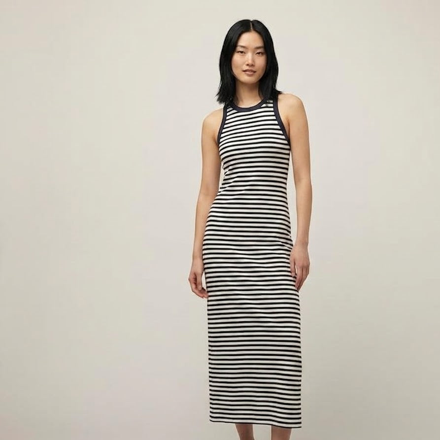 A woman modeling a sleeveless black and white horizontally striped midi dress with a halter-style neckline, paired with black flat shoes, against a plain light gray studio background.