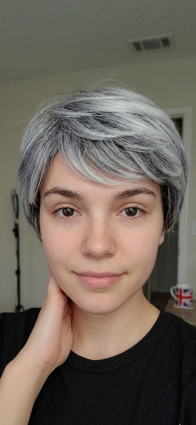 Person with short, styled hair in a neutral indoor setting